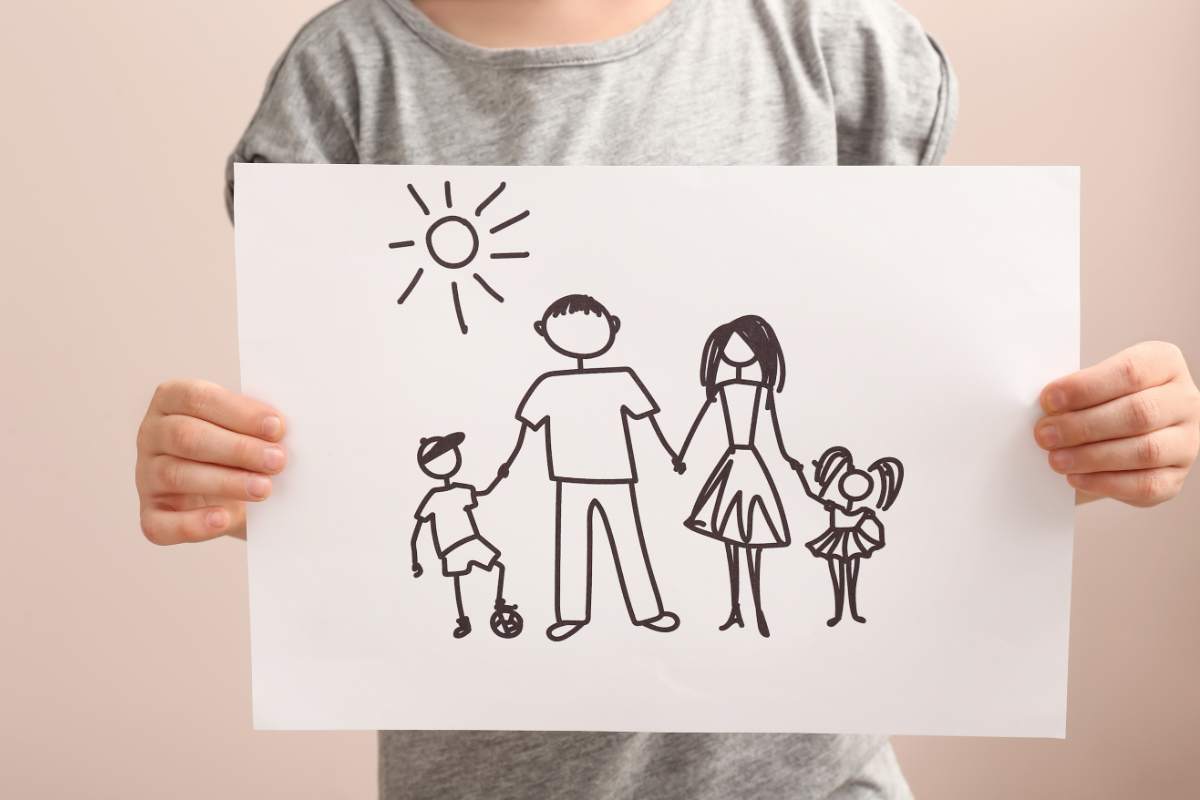 bambino con in mano un disegno di una famiglia