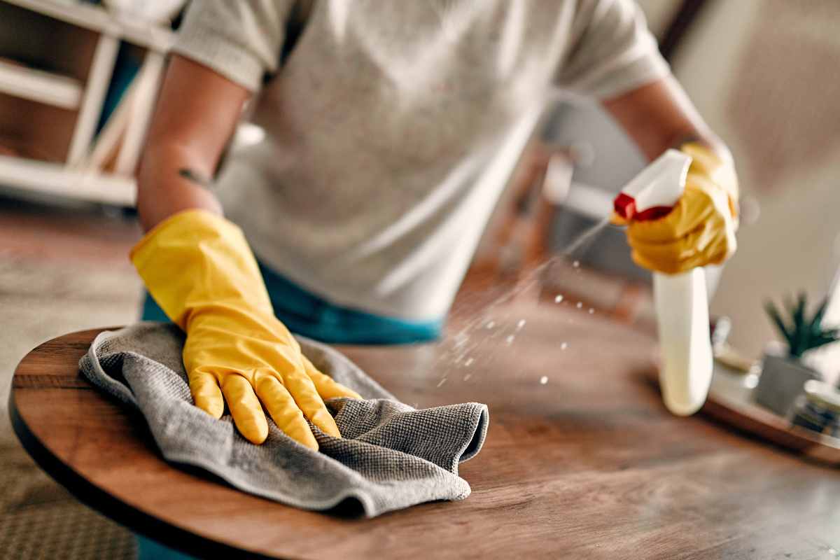 donna pulisce superfice con spray e un panno
